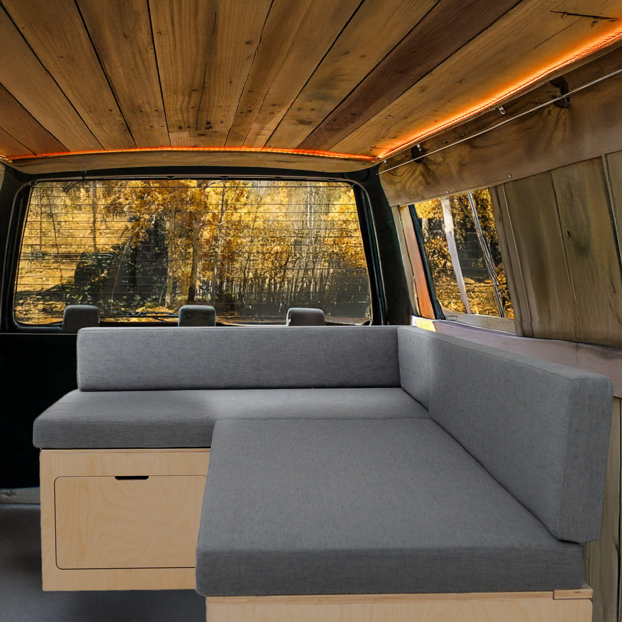 L-förmiges Bett für Wohnmobile in Grau mit Stauraum, modernes Design, gepolsterte Sitzfläche und Holzverkleidung, ideal für gemütliche Räume