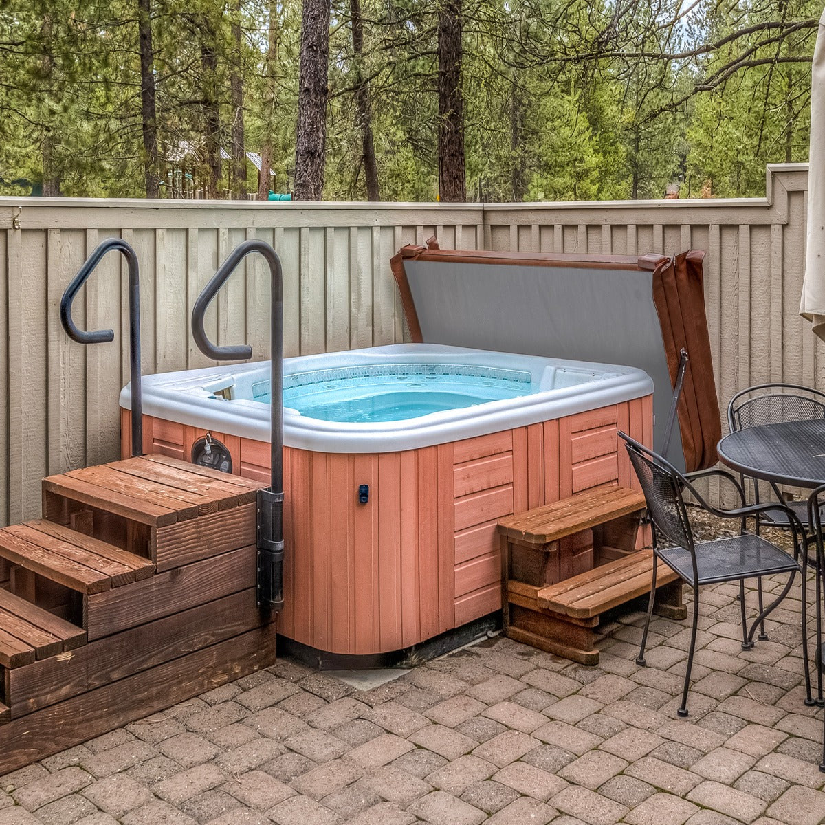 Braune 2m Whirlpool-Abdeckung auf einem Holzdeck, umgeben von Bäumen, mit einem eleganten, modernen Design und robustem Material