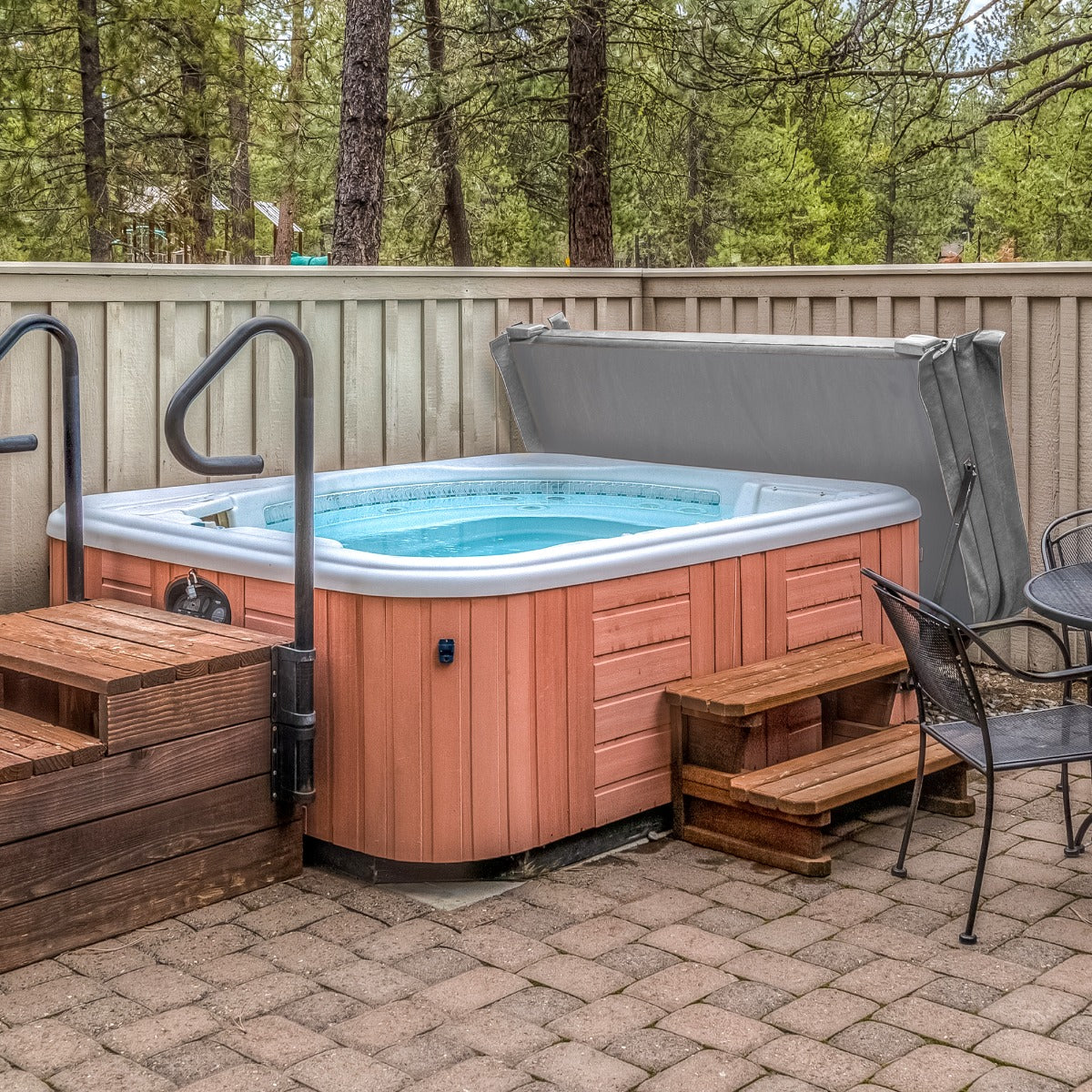 Grau beschichtete Whirlpool-Abdeckung für 2,2 m großen Whirlpool, umgeben von Holzstufen und einem gepflasterten Boden, ideal für Gartenbereiche