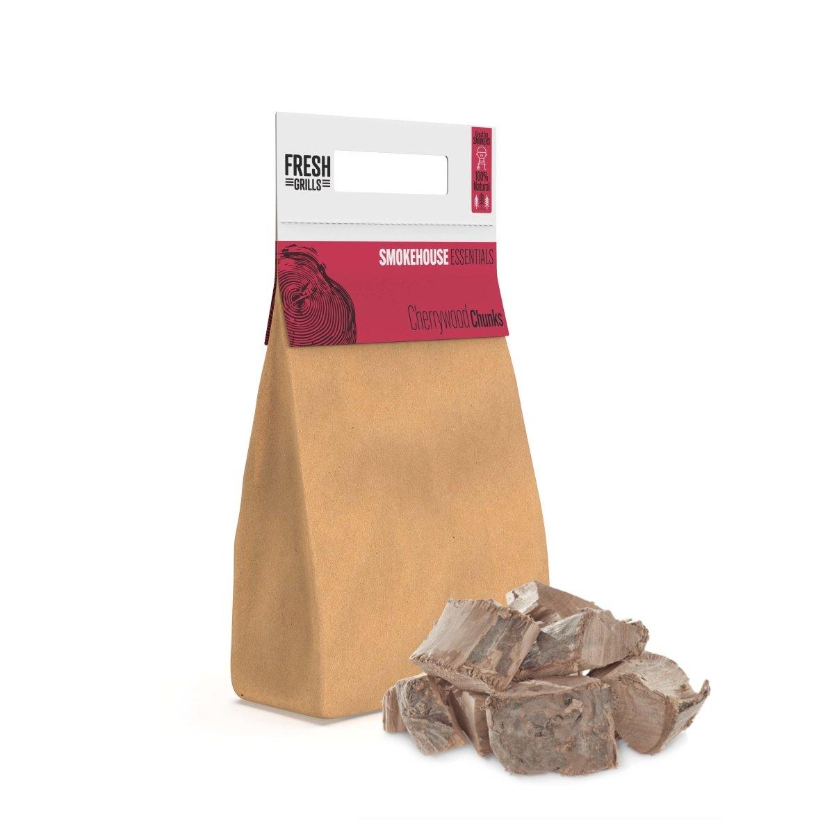 Braune Papiertüte mit rotem Etikett, gefüllt mit großen, groben Kirschholzstücken für BBQ-Räucherzwecke, ideal für intensives Raucharoma