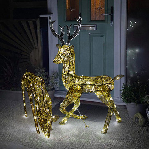 Zwei LED-beleuchtete Rentiere in Gold, eines 61 cm und das andere 1,2 m hoch, mit funkelnden Lichtern, stehen vor einer Haustür in festlicher Atmosphäre