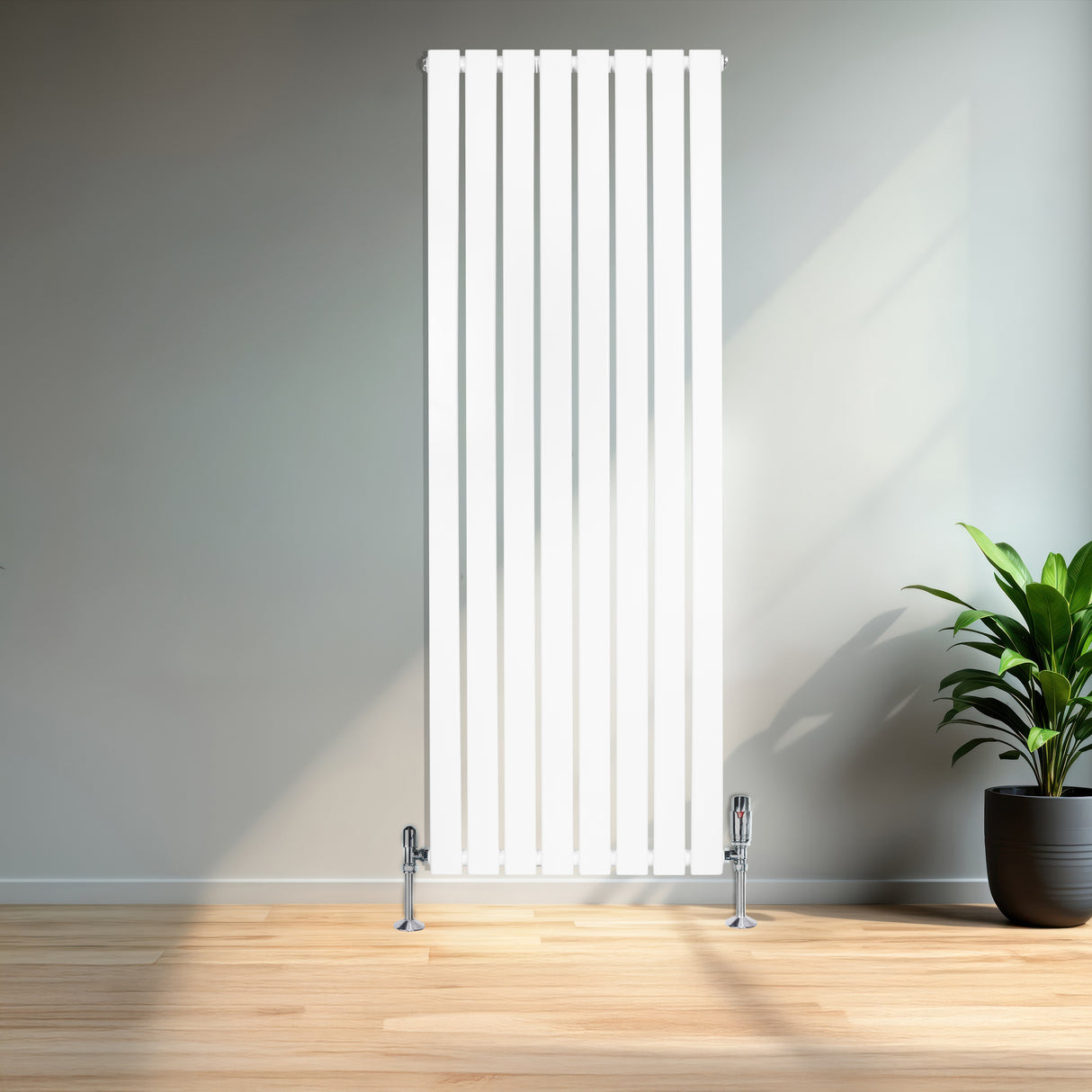Flachheizkörper in Weiß, 1600mm x 560mm, mit vertikalen Lamellen und glänzenden Füßen, steht vor einer hellen Wand und einer grünen Pflanze