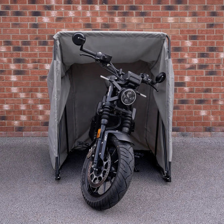 Ein graues Motorradzelt schützt ein schwarzes Motorrad vor Witterungseinflüssen, mit stabilen Stangen und einem robusten Stoff