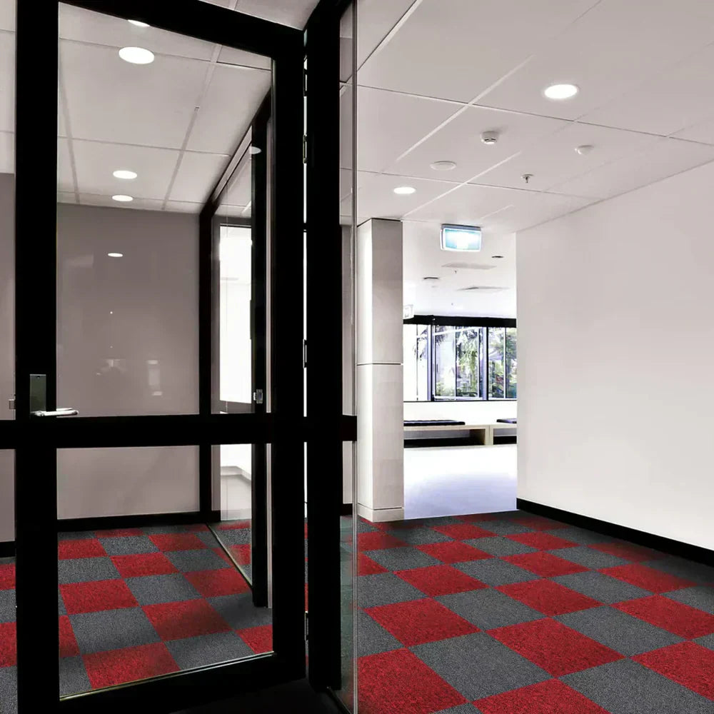 Moderne Teppichfliesen in rot und grau, verlegt in einem hellen Flur mit großen Fenstern und minimalistischer Einrichtung