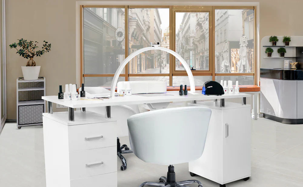 Moderne Nagelstudio-Einrichtung mit weißem Tisch, ergonomischem Stuhl, Nagellackfläschchen und großen Fenstern, die Tageslicht hereinlassen