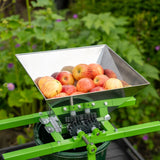 Tragbarer Obstzerkleinerer mit Kurbel, grüne Struktur, Edelstahlbehälter gefüllt mit frischen Äpfeln, ideal für die Obstverarbeitung