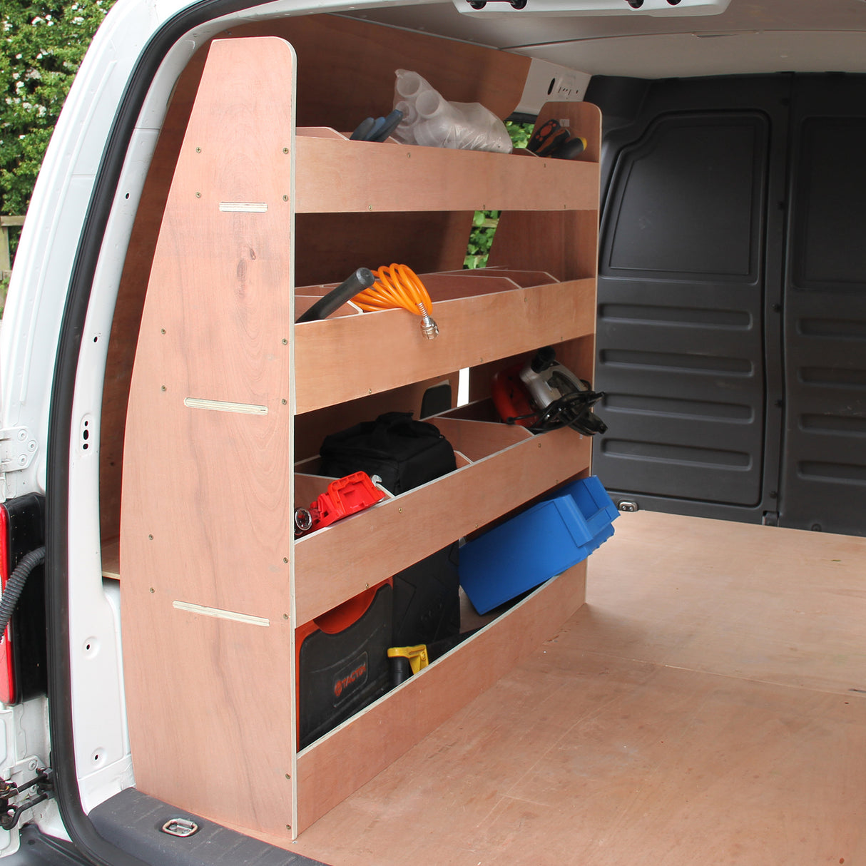 Rauchgraue Transporterverkleidung mit einem Regalsystem im VW Caddy, bestehend aus mehreren Fächern für Werkzeuge und Ausrüstung, aus robustem Holz gefertigt