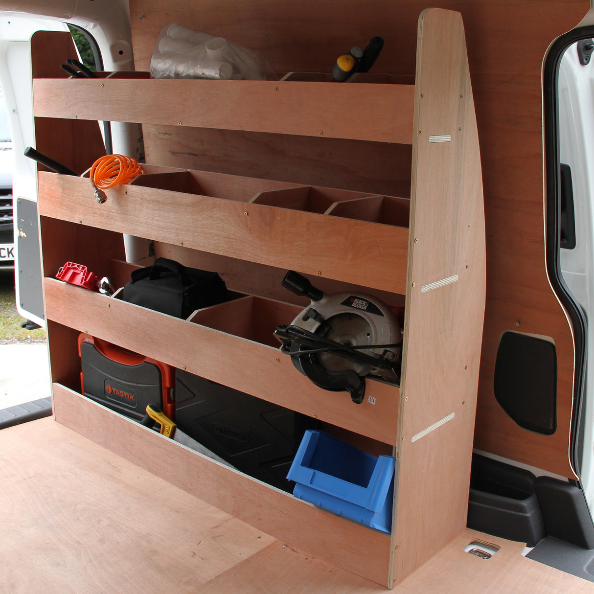 Schwarze Van-Verkleidung mit Regalsystem, Holzregale für Werkzeuge, orange Kabel, und eine blaue Box, ideal für VW Caddy und Transporter
