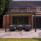 Anthrazitfarbene Aluminium-Pergola mit LED-Beleuchtung, 3 m x 3 m, umgeben von einer modernen Lounge-Ecke und einem eleganten Tisch auf einem gepflasterten Boden