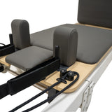 Pilates Reformer Maschine aus Aluminium mit grauem Polster, verstellbaren Fußstützen und elastischen Widerstandsbändern für vielseitiges Training