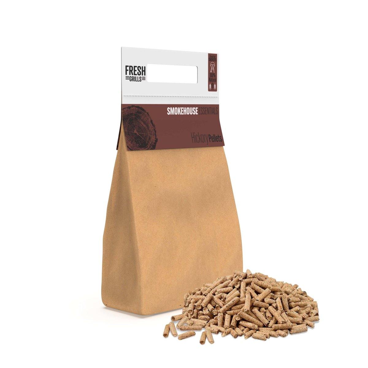 Braune Papiertüte mit Hickory-Räucherpellets, daneben ein Haufen kleiner, gleichmäßiger Holzpellets, ideal für BBQ und Grillen