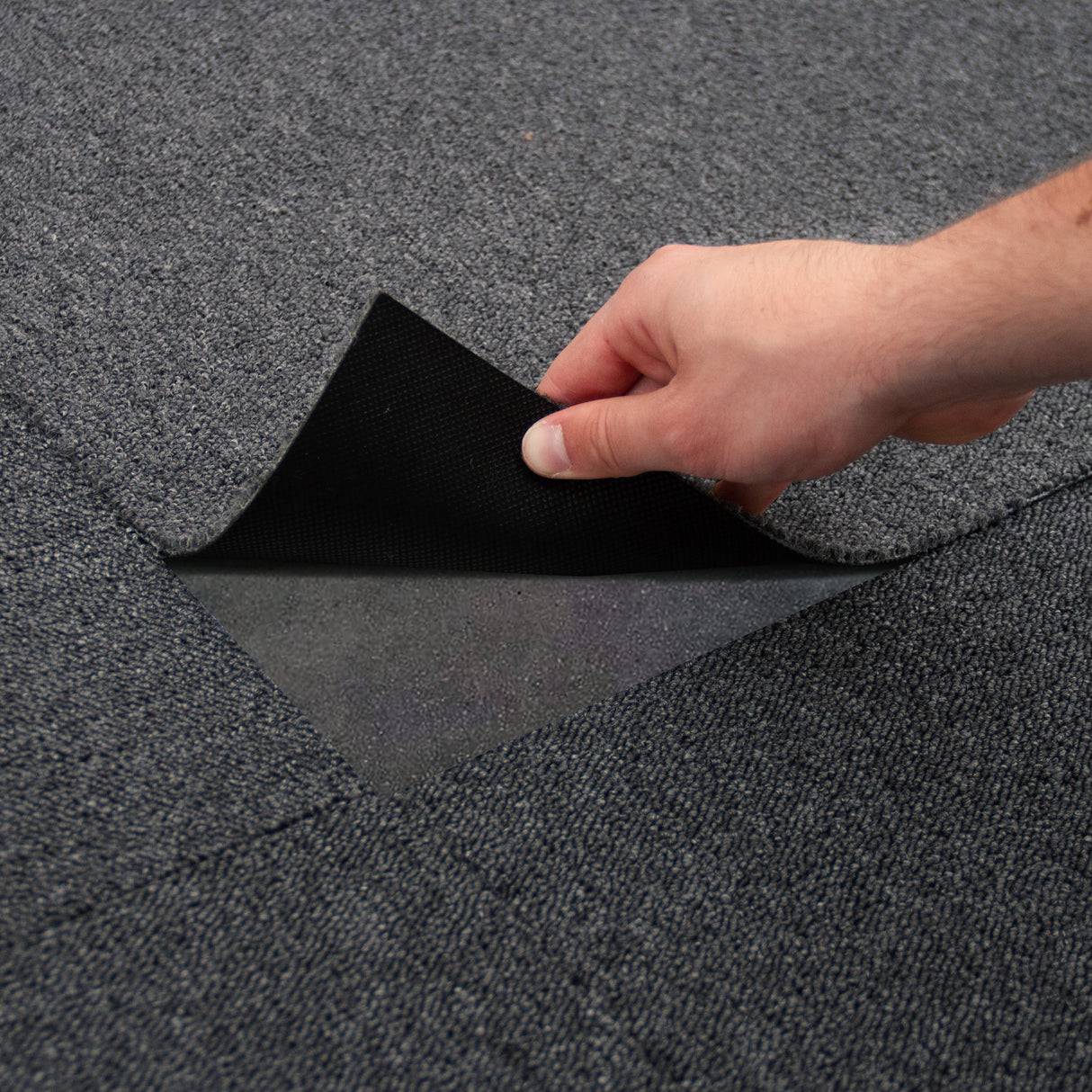 Anthrazitfarbene Teppichfliesen in einem modernen Design, handlich zum Verlegen, mit einer strukturierten Oberfläche und rutschfester Unterseite