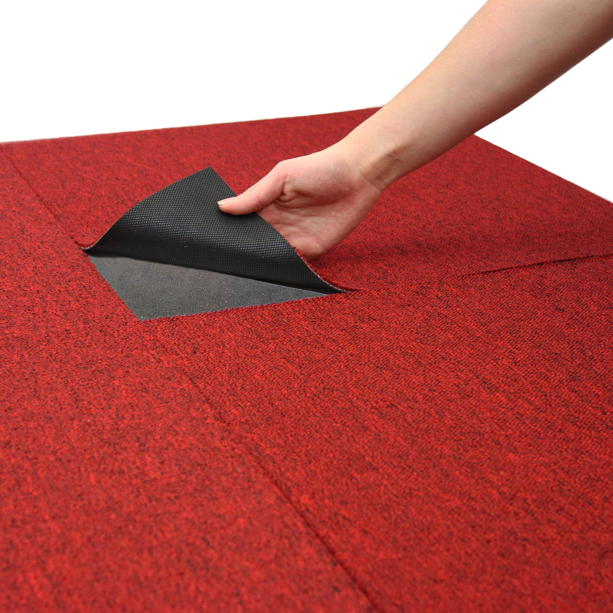 Scharlachrote Teppichfliesen in einem Quadrat, eine Hand hebt eine Fliese an, um die darunterliegende Struktur zu zeigen, samtige Textur und strapazierfähiges Material
