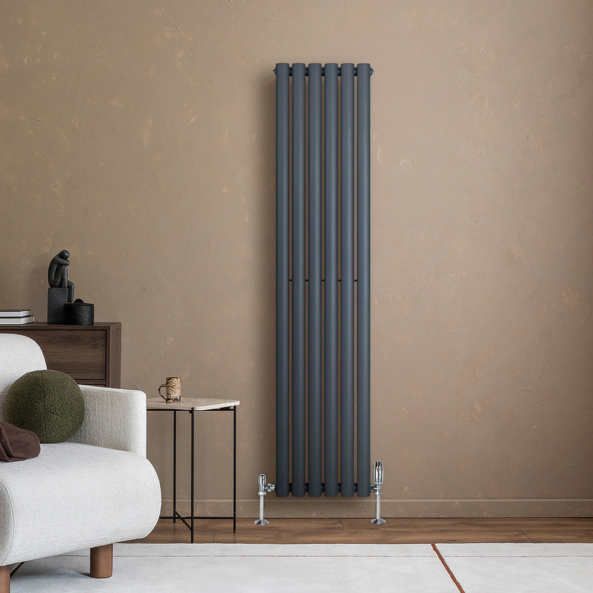 Anthrazitgrauer Gliederheizkörper mit TRV Chromventilen, 1600mm x 360mm, an einer warmen Wand, neben einem modernen Sofa und Beistelltisch