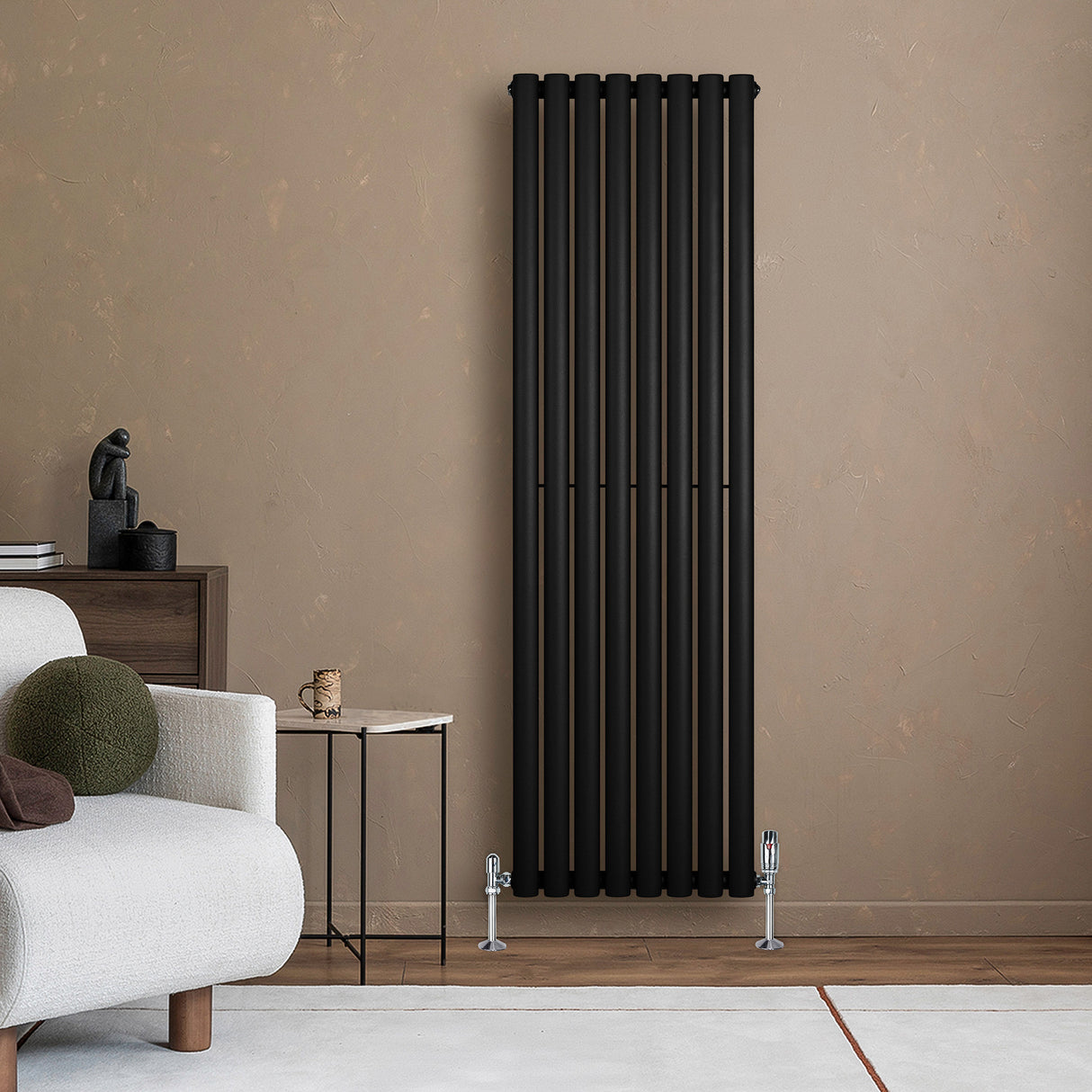 Schwarzer Gliederheizkörper mit TRV Chromventilen, 1600mm x 480mm, an einer neutralen Wand, umgeben von moderner Einrichtung und Möbeln