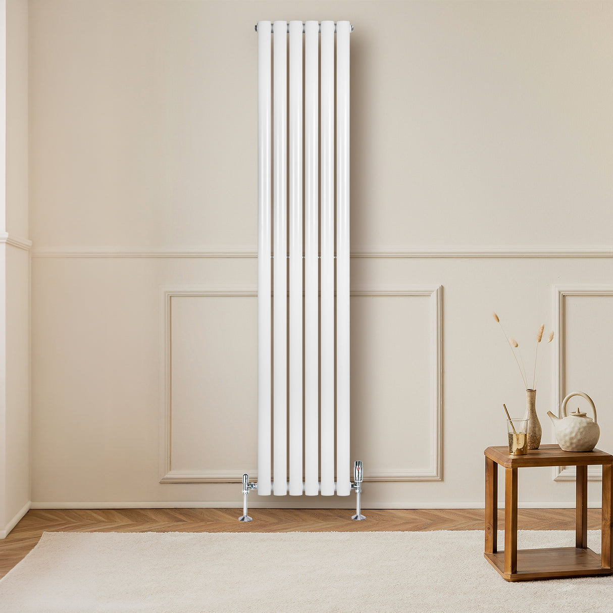Hochformatiger, weißer Gliederheizkörper mit TRV Chromventilen, elegant an einer hellen Wand montiert, ergänzt durch einen stilvollen Holztisch im Vordergrund