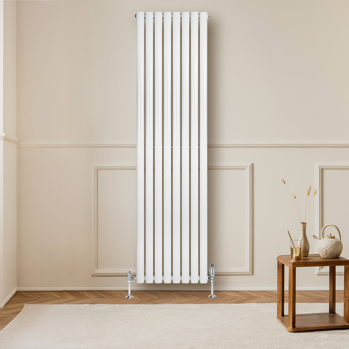 Hochformatiger, weißer Gliederheizkörper mit TRV Chromventilen, elegant an einer hellen Wand montiert, ergänzt durch einen stilvollen Holztisch im Vordergrund