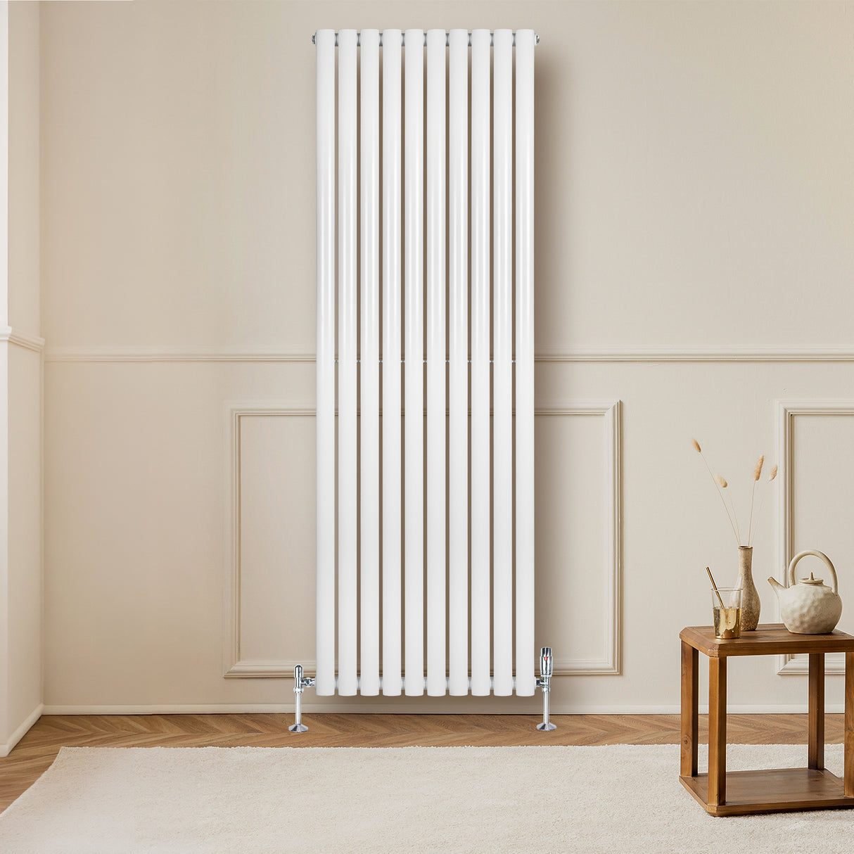 Hochformatiger, weißer Gliederheizkörper mit TRV Chromventilen, elegant an einer hellen Wand montiert, neben einem Holzkaffee-Tisch in modernem Raum