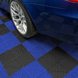 Sechseckige, belüftete Garagenbodenfliesen in Schwarz und Blau, mit rutschfester Oberfläche und Kantenschutz, unter einem blauen Auto platziert