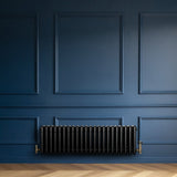 Schwarzer Röhrenheizkörper mit vier Säulen, 300mm x 1010mm, elegant an einer blauen Wand montiert, verleiht dem Raum einen modernen Look
