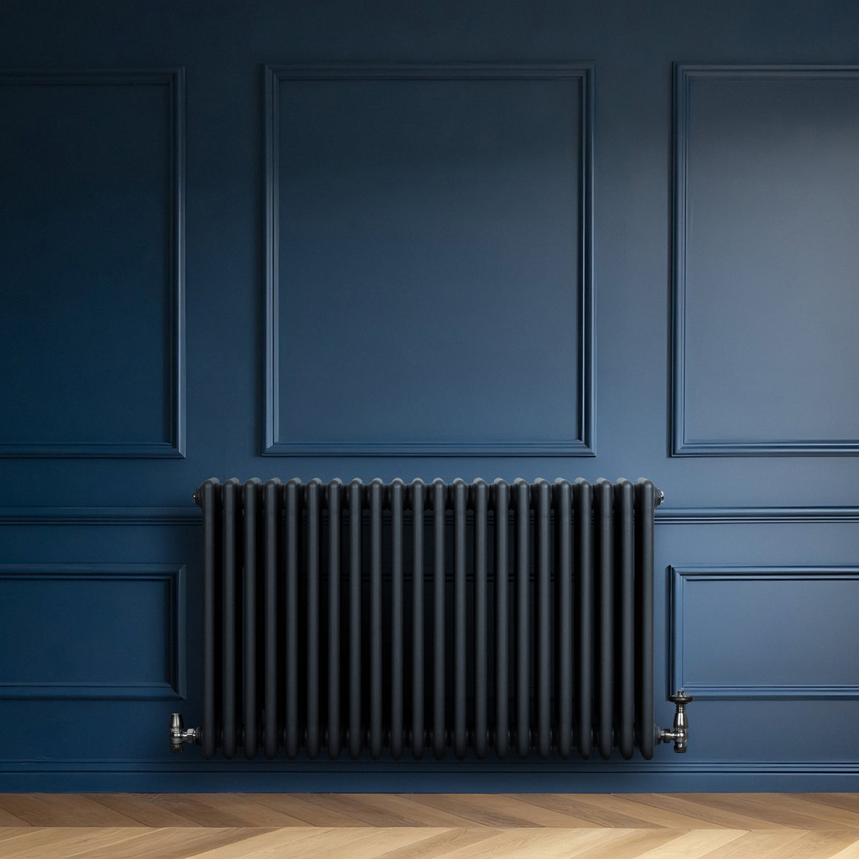 Röhrenheizkörper mit 4 Säulen in Anthrazitgrau, 600mm x 1010mm, vor einer blauen Wand, mit glänzender Oberfläche und eleganten, runden Formen
