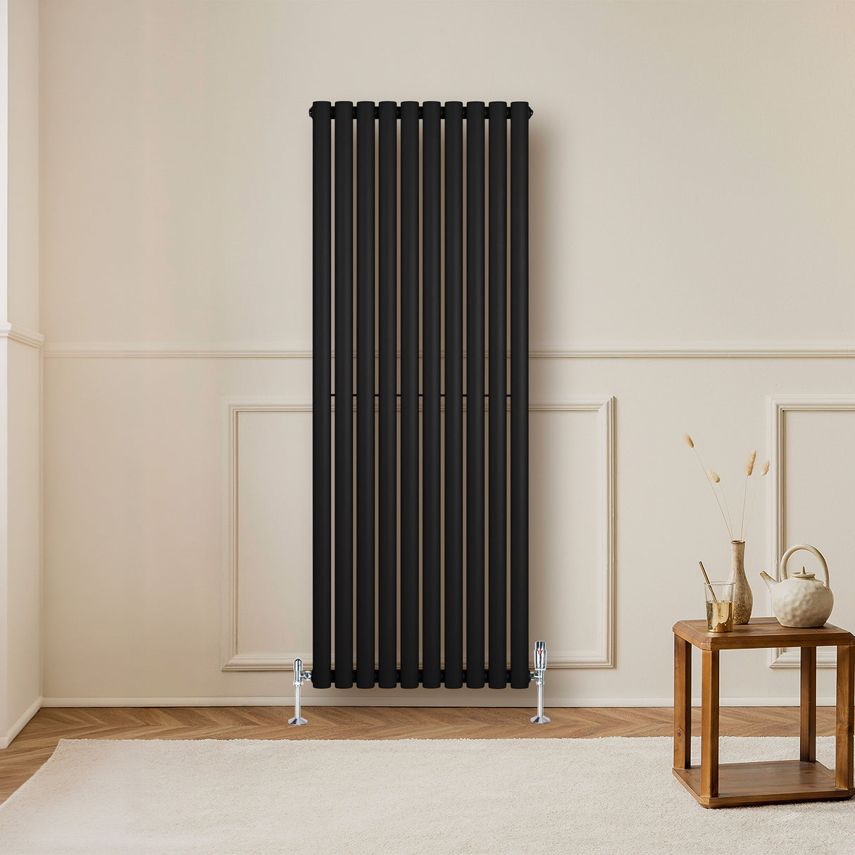 Schwarzer Gliederheizkörper mit vertikalen Lamellen, 1600mm x 600mm, elegant an einer hellen Wand, ergänzt durch einen modernen Holztisch und Dekoration
