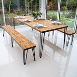 Ein modernes Esszimmer-Set mit einem rechteckigen Holztisch und zwei Bänken, alle mit schwarzen Metallbeinen, auf einem hellen, glänzenden Boden