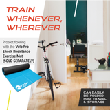 Silberner Velo Pro magnetischer Turbo Trainer mit einem stabilen Rahmen, platziert in einem hellen Raum mit Holzfußboden und Fitnessmatte